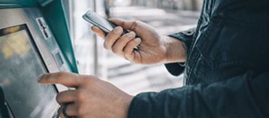 Image of a person using their phone and ATM