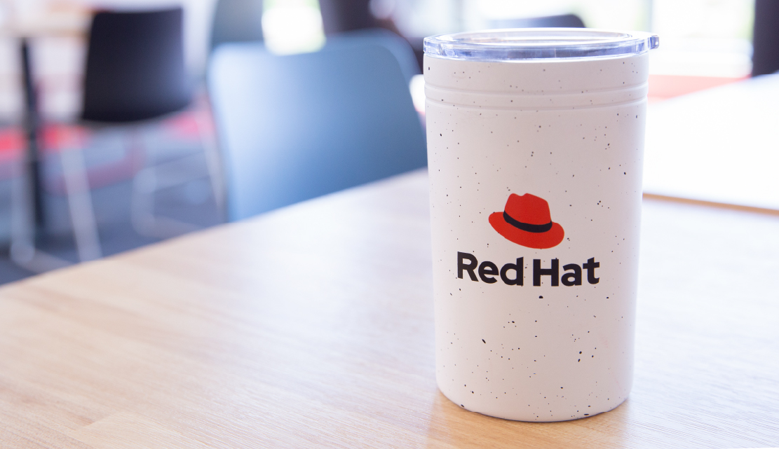 Photograph of a coffee tumbler with Red Hat logo B version printed on the front.
