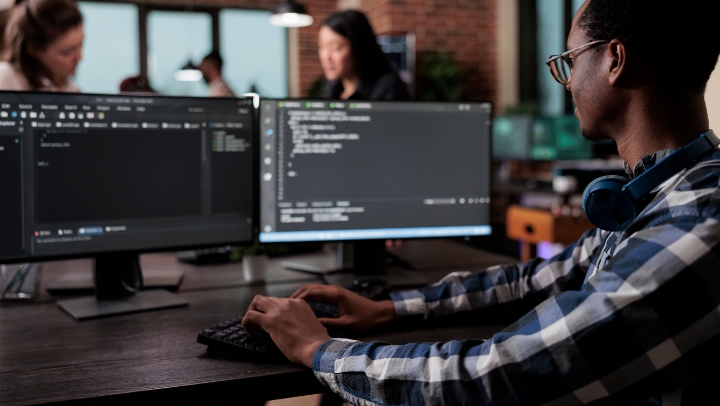 开发人员在两个计算机屏幕前编写代码